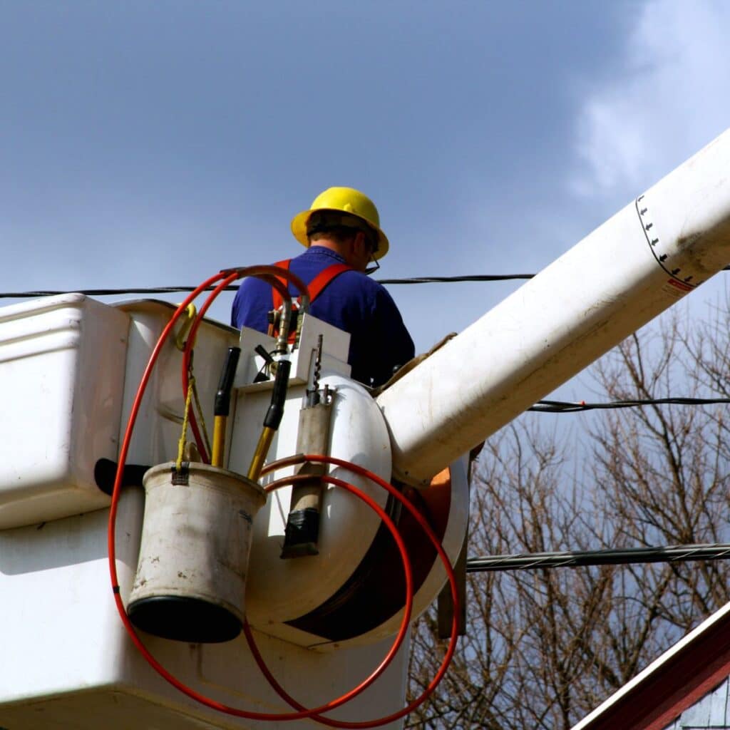 technician in a bucket of a bucket truck performing electrical services