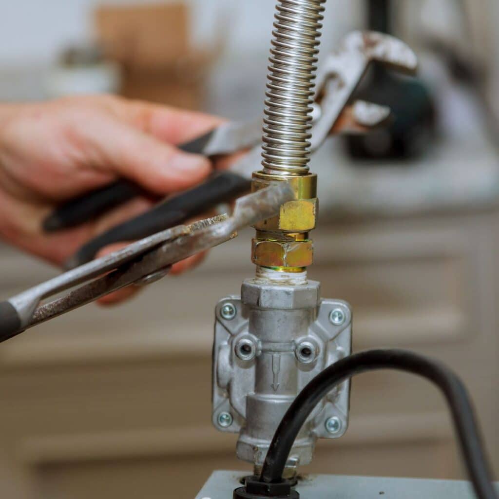 closeup of a gas line being worked on with wrenches by a plumber