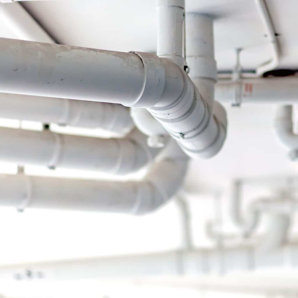 closeup of large white pipes positioned on the ceiling of a commercial building