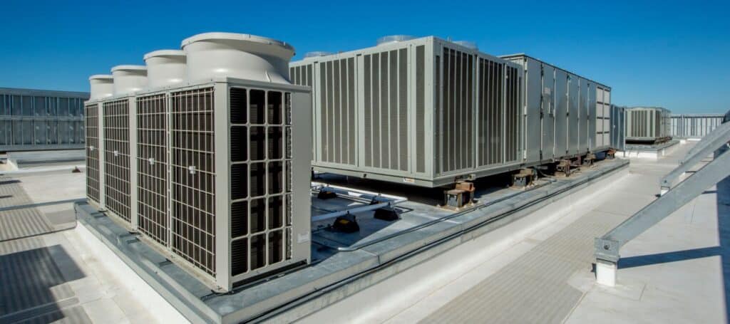 commercial units on top of a commercial building, Experienced HVAC technician testing system performance with professional diagnostic tools
