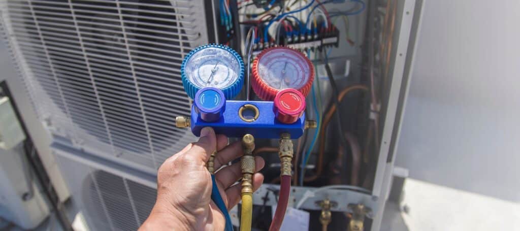 hvac technician holding a manifold pressure gauge running a tune up, Homeowner reviewing affordable HVAC repair options during service appointment