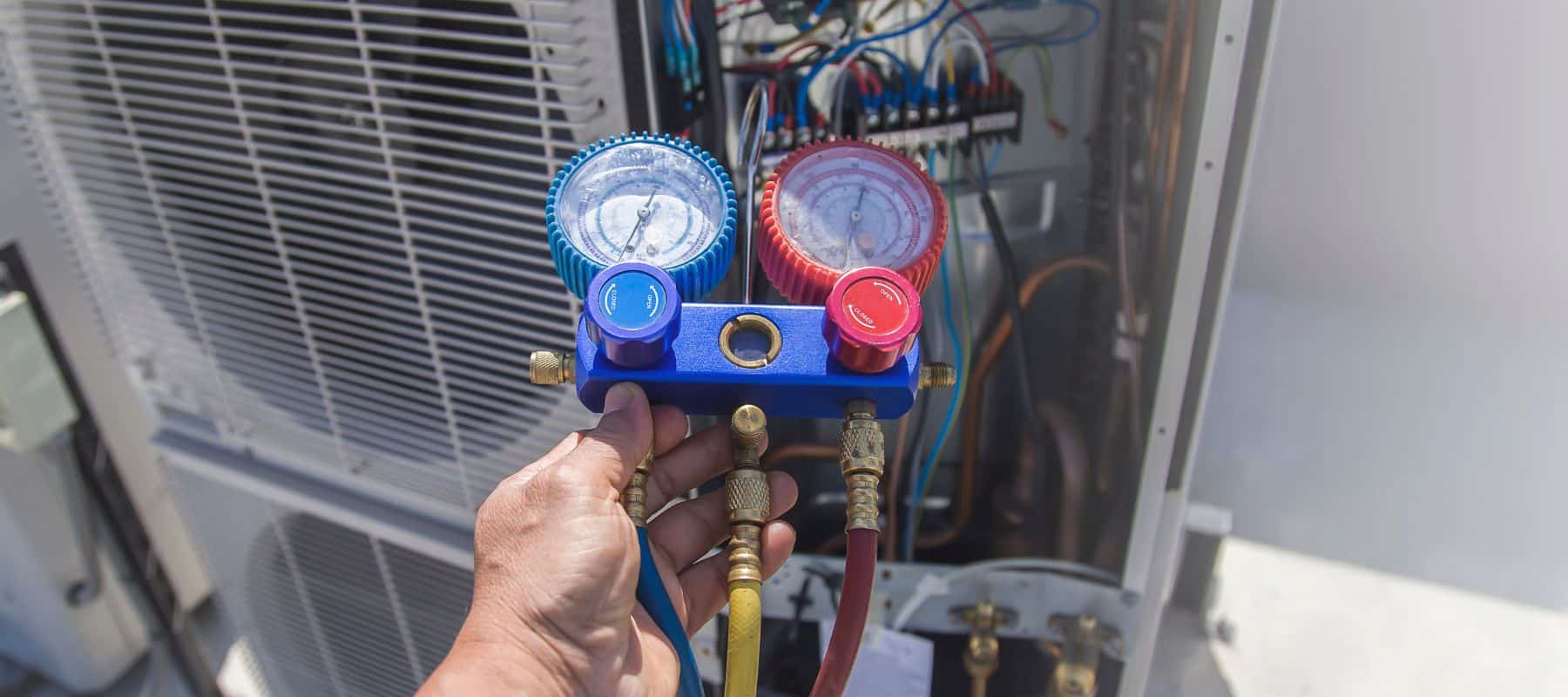 hvac technician holding a manifold pressure gauge running a tune up