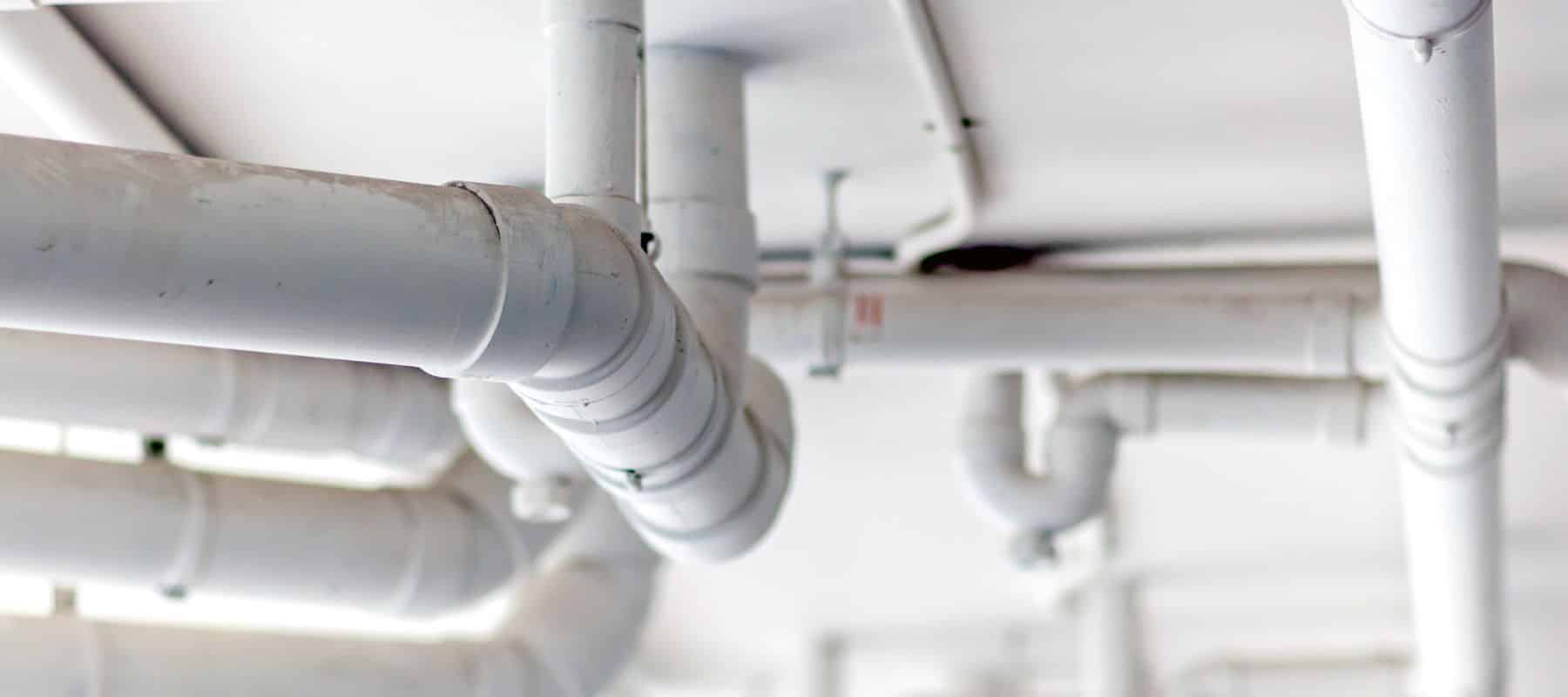 closeup of large white pipes positioned on the ceiling of a commercial building