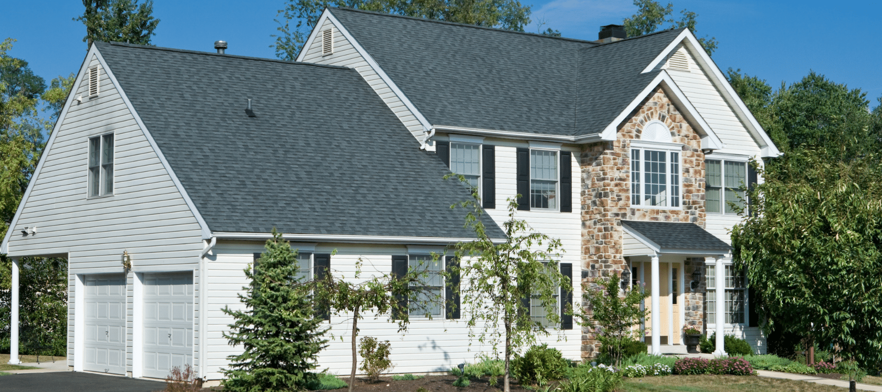 closeup of a white house with stone features in lansdale pennsylvania surrounded by green trees and bushes