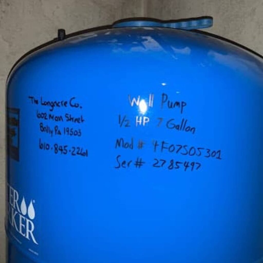 Blue well tank labeled with specifications and contact information for The Longacre Company