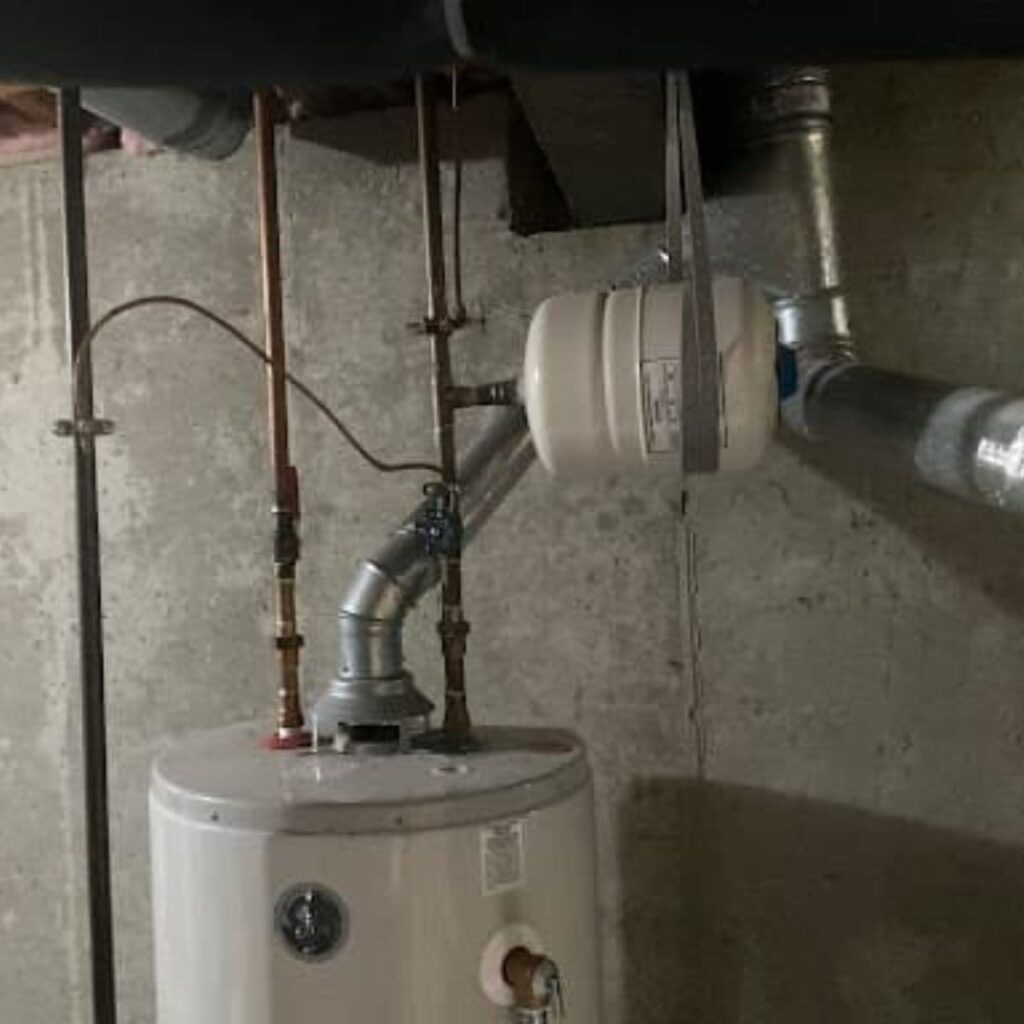 White residential water heater with surrounding copper plumbing and an expansion tank mounted above