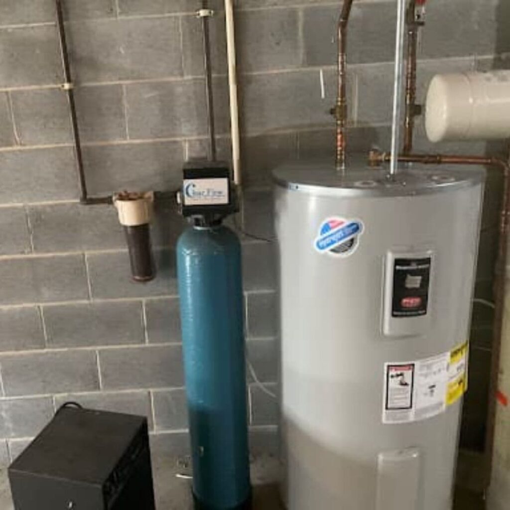 Basement setup featuring a modern water heater and a tall blue water softener system next to a concrete wall