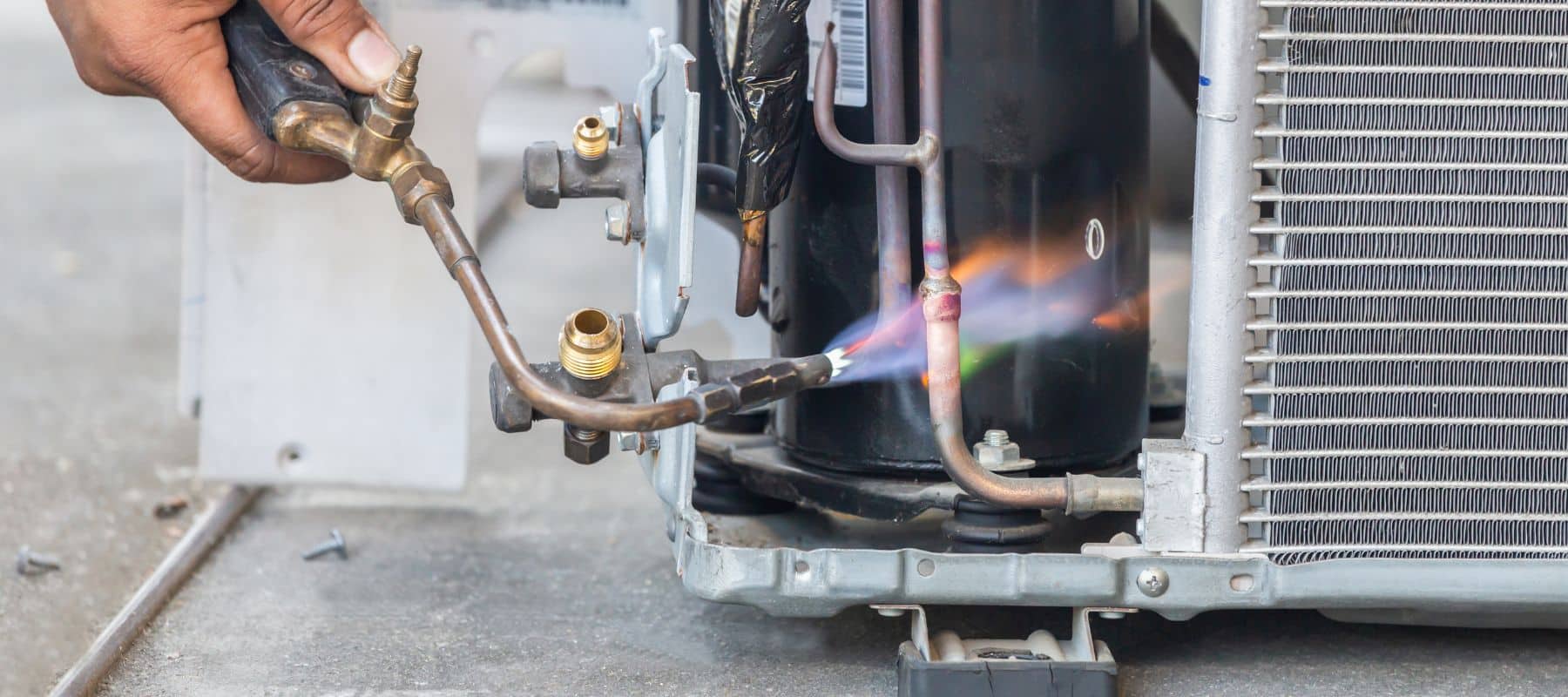 closeup of an hvac technician using a small blow torch to perform hvac repairs