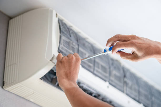 Technician restoring airflow to malfunctioning home air conditioner during humid afternoon