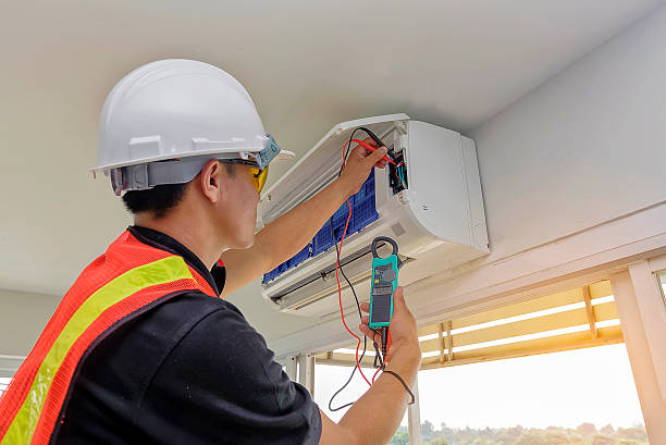 Experienced HVAC technician testing AC system performance with diagnostic tools indoors