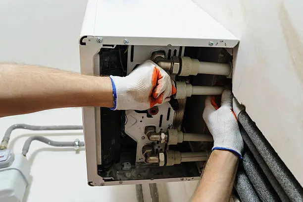 Technician performing Heater Repair beside a gas furnace in a Bethlehem - PA utility room