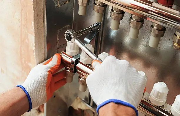 Specialist performing Heater Repair on an aging furnace inside an Emmaus - PA utility room