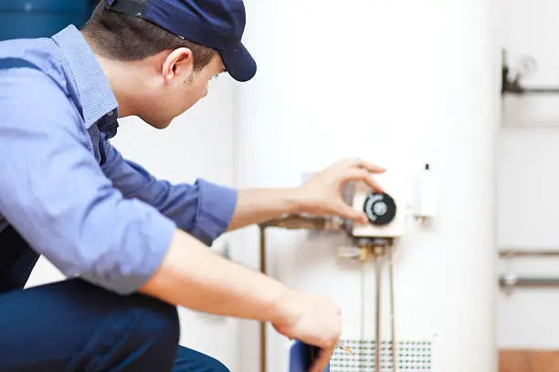 Technician performing Heater Repair beside an older furnace inside an Easton - PA row home